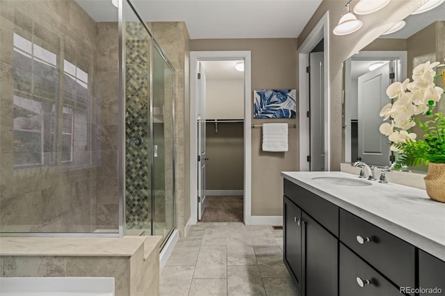 full bath with tile patterned flooring, vanity, baseboards, a spacious closet, and a stall shower