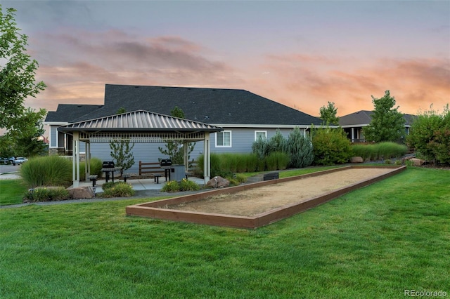 back of house at dusk featuring a yard and a gazebo