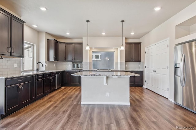 kitchen with a kitchen island, stainless steel fridge with ice dispenser, dark brown cabinetry, decorative light fixtures, and dark hardwood / wood-style flooring