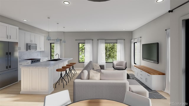 living room with plenty of natural light, sink, and light hardwood / wood-style flooring