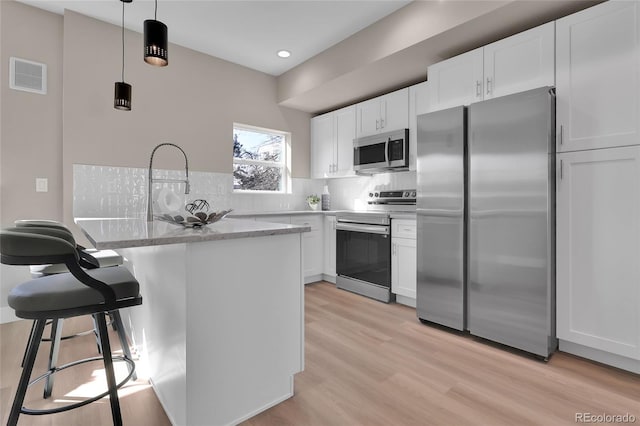 kitchen with visible vents, backsplash, appliances with stainless steel finishes, and white cabinetry