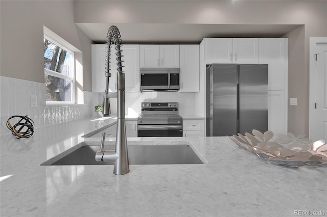 kitchen featuring white cabinetry, light stone countertops, and appliances with stainless steel finishes