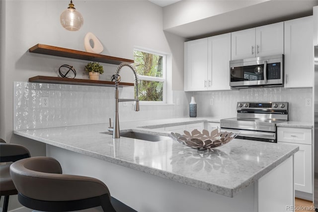 kitchen featuring open shelves, a sink, appliances with stainless steel finishes, and tasteful backsplash