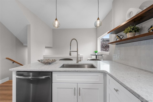kitchen featuring decorative backsplash, light stone countertops, dishwasher, a sink, and white cabinets