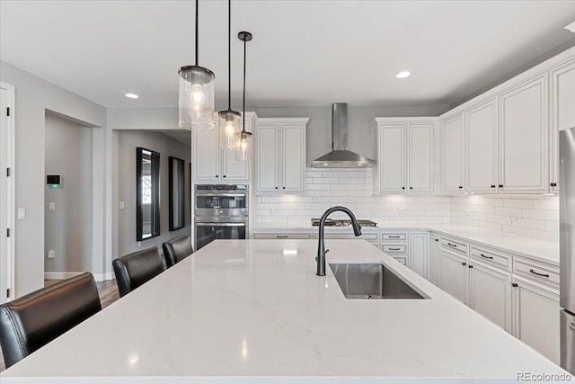 7074 S Vandriver Ct, Aurora, CO 80016 - kitchen featuring wall chimney exhaust hood, stainless steel appliances, decorative backsplash, a large island with sink, and white cabinets