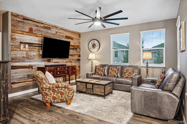 living room with ceiling fan, wood walls, and dark hardwood / wood-style flooring