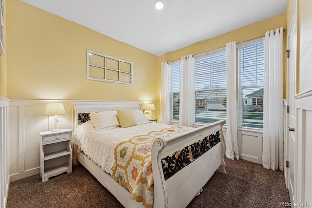 bedroom featuring multiple windows and dark colored carpet