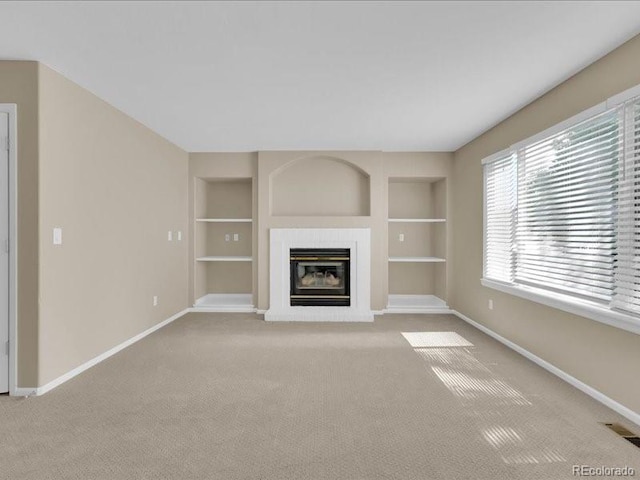 8906 Miners Dr, Highlands Ranch, CO 80126 - unfurnished living room with built in shelves, carpet, and a glass covered fireplace