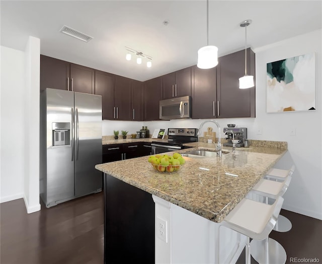 1062 Rockhurst Dr Unit 302, Highlands Ranch, CO 80129 - kitchen featuring appliances with stainless steel finishes, a sink, a peninsula, dark brown cabinets, and a breakfast bar area