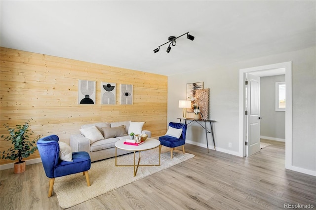 living area with wood finished floors, baseboards, and wooden walls