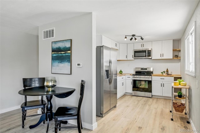 kitchen with stainless steel appliances, light wood-type flooring, white cabinets, light countertops, and baseboards