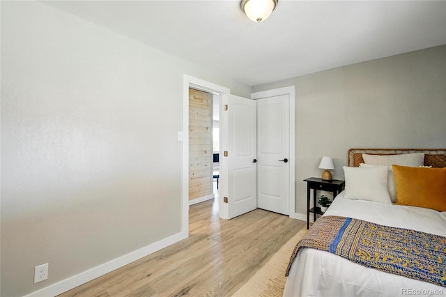 bedroom with light wood-type flooring, baseboards, and a closet
