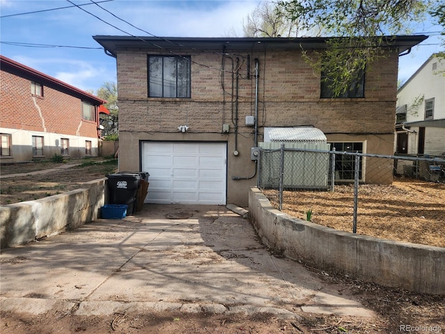 1822 E Pikes Peak Ave, Colorado Springs, CO 80909 - rear view of house featuring an attached garage, brick siding, fence, and concrete driveway