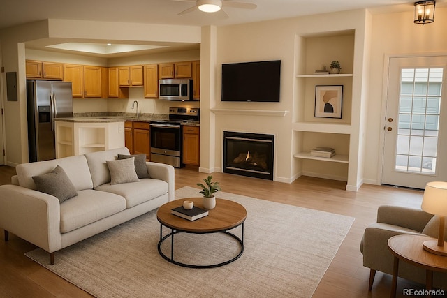 2980 W Centennial Dr Unit L, Littleton, CO 80123 - living room featuring built in shelves, light wood-style floors, ceiling fan, baseboards, and a glass covered fireplace