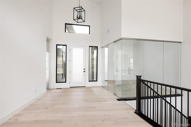 entrance foyer featuring a towering ceiling, light hardwood / wood-style floors, and an inviting chandelier