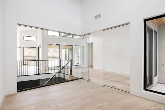 empty room with a high ceiling and light wood-type flooring