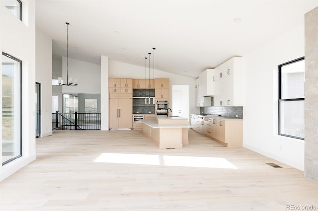 kitchen featuring backsplash, a wealth of natural light, a kitchen island, and pendant lighting