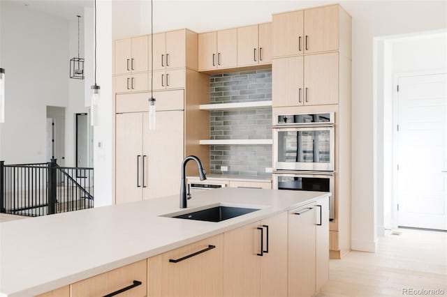 kitchen with light brown cabinets, light wood-type flooring, sink, and double oven