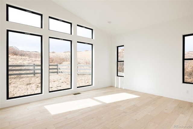 unfurnished room with light hardwood / wood-style flooring and lofted ceiling