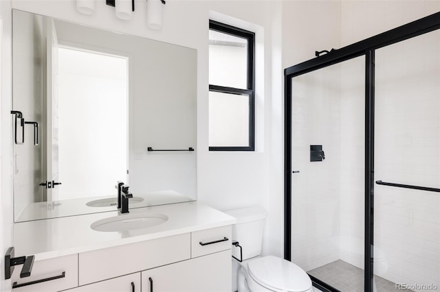 bathroom featuring vanity, toilet, a shower with door, and a healthy amount of sunlight