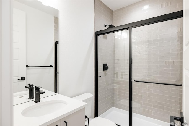 bathroom featuring vanity, toilet, and a shower with shower door