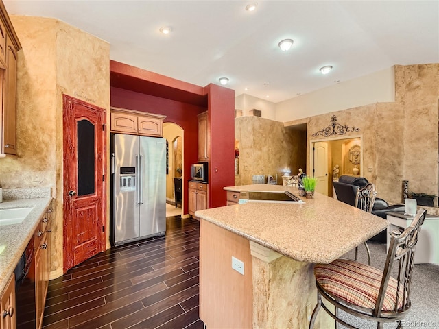 kitchen with a kitchen breakfast bar, sink, appliances with stainless steel finishes, a kitchen island, and dark hardwood / wood-style flooring