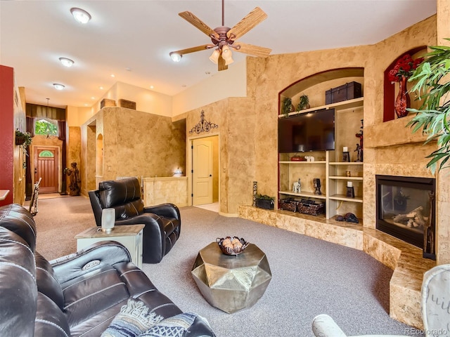 carpeted living room with ceiling fan, a high end fireplace, and built in shelves