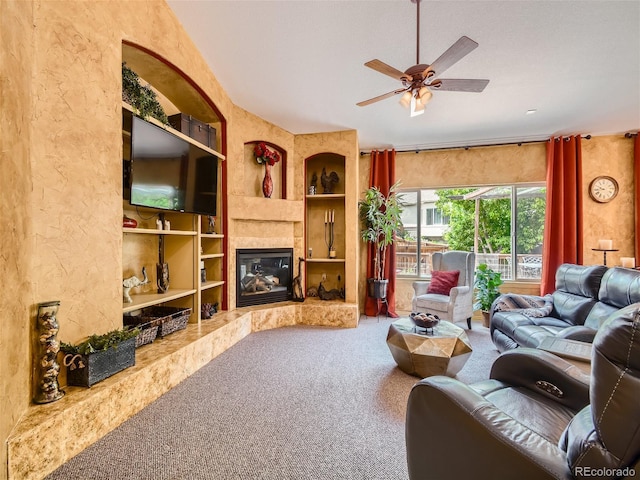 living room featuring a high end fireplace, built in shelves, carpet flooring, and ceiling fan