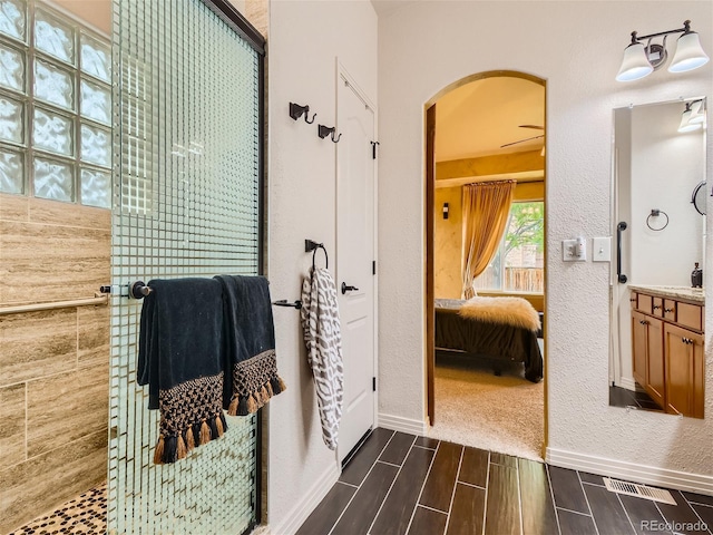 bathroom featuring ceiling fan, vanity, and walk in shower