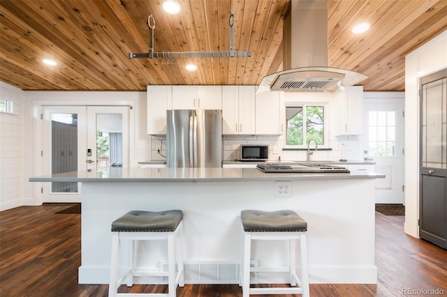 7695 Quitman St, Westminster, CO 80030 - kitchen featuring appliances with stainless steel finishes, island range hood, wood ceiling, decorative backsplash, and white cabinetry