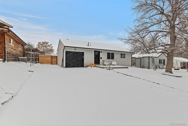 snow covered rear of property with an outdoor structure