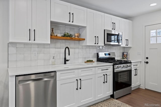 kitchen featuring decorative backsplash, stainless steel appliances, white cabinetry, and sink