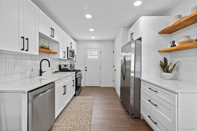 kitchen with sink, stainless steel appliances, backsplash, hardwood / wood-style floors, and white cabinets