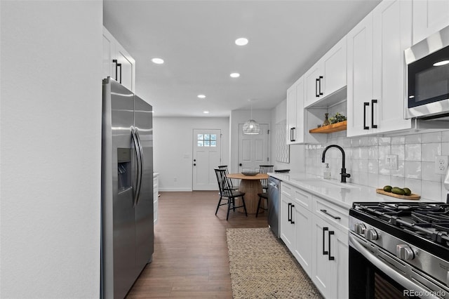 kitchen with backsplash, sink, light stone countertops, white cabinetry, and stainless steel appliances