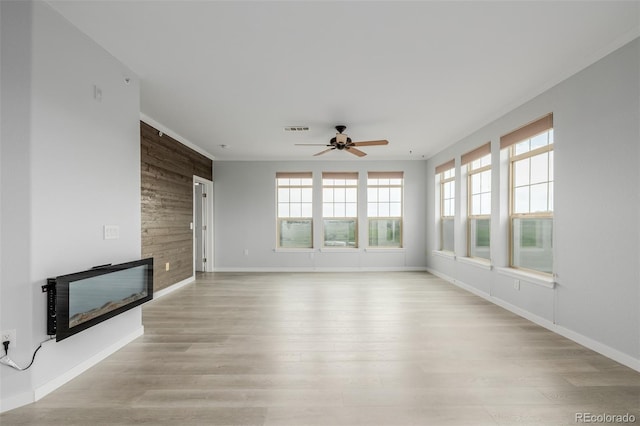 13456 Via Varra Unit 401, Broomfield, CO 80020 - unfurnished living room with plenty of natural light, a glass covered fireplace, a ceiling fan, wooden walls, and light wood-style floors