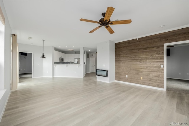 13456 Via Varra Unit 401, Broomfield, CO 80020 - unfurnished living room with wood walls, a ceiling fan, light wood-style flooring, an accent wall, and recessed lighting