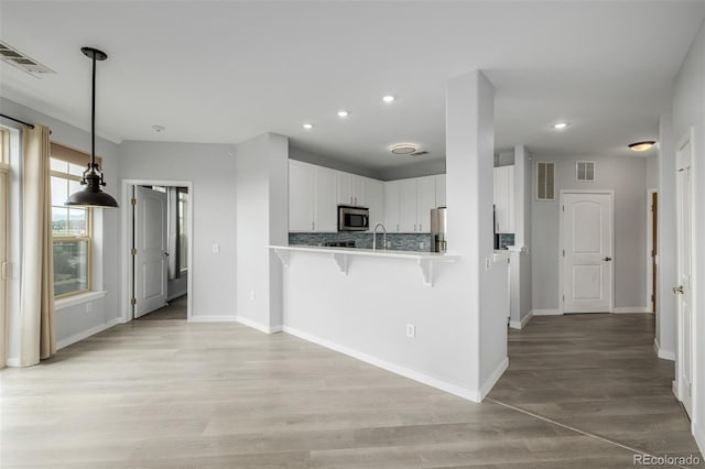 13456 Via Varra Unit 401, Broomfield, CO 80020 - kitchen featuring stainless steel appliances, a kitchen breakfast bar, white cabinets, recessed lighting, and light wood-style flooring