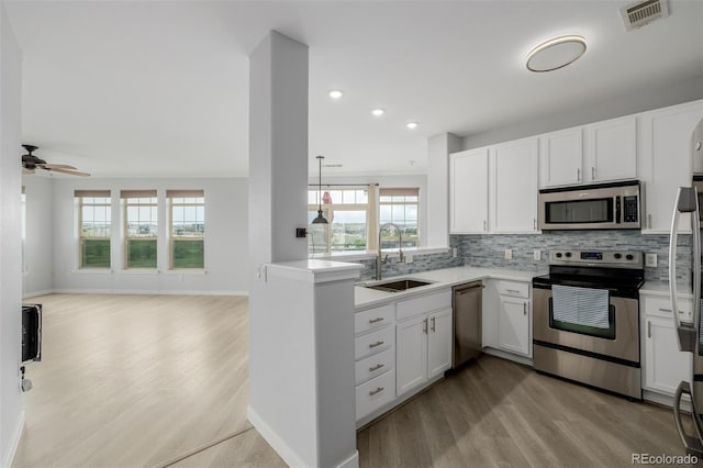 13456 Via Varra Unit 401, Broomfield, CO 80020 - kitchen featuring appliances with stainless steel finishes, light wood-style floors, open floor plan, tasteful backsplash, and light countertops