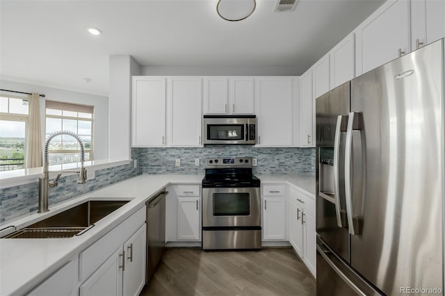 13456 Via Varra Unit 401, Broomfield, CO 80020 - kitchen featuring stainless steel appliances, wood finished floors, tasteful backsplash, white cabinetry, and light countertops