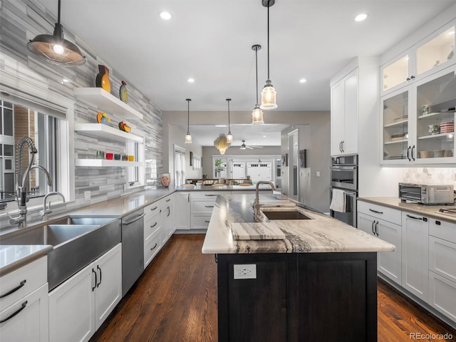 kitchen with appliances with stainless steel finishes, sink, tasteful backsplash, white cabinetry, and a center island with sink