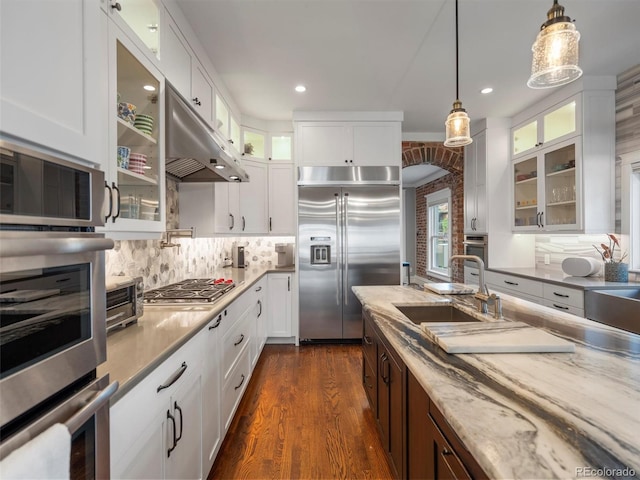 kitchen featuring sink, stainless steel appliances, white cabinetry, and light stone countertops