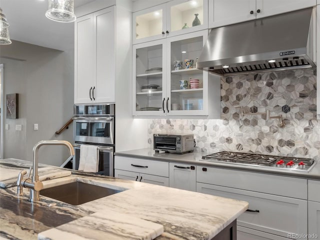 kitchen with sink, backsplash, white cabinets, and extractor fan