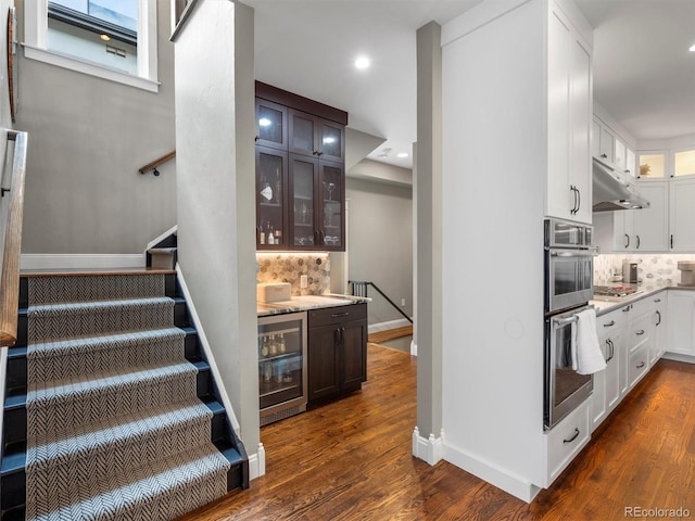 stairway with wood-type flooring and wine cooler