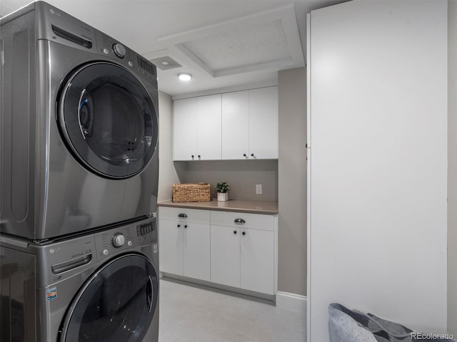 washroom featuring stacked washer / dryer and cabinets