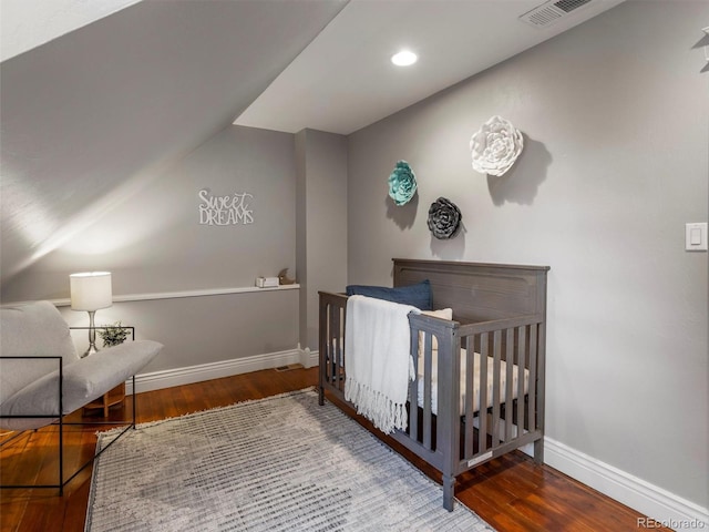 bedroom with hardwood / wood-style floors and a crib