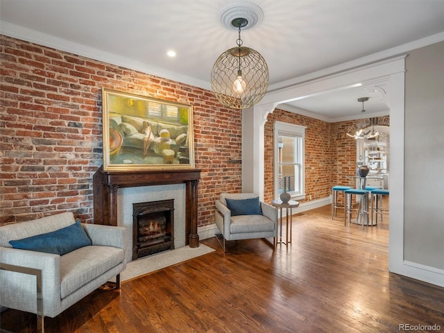 living area with hardwood / wood-style flooring, brick wall, and crown molding