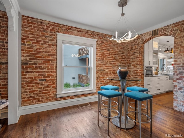 unfurnished dining area with brick wall, dark hardwood / wood-style floors, and ornamental molding