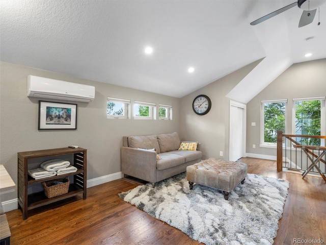 living room with lofted ceiling, an AC wall unit, dark hardwood / wood-style floors, and a healthy amount of sunlight