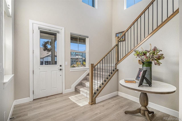 entryway with a towering ceiling and light hardwood / wood-style flooring