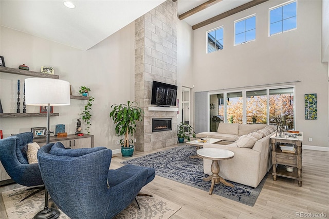 living room with high vaulted ceiling, a tiled fireplace, light hardwood / wood-style floors, and beamed ceiling